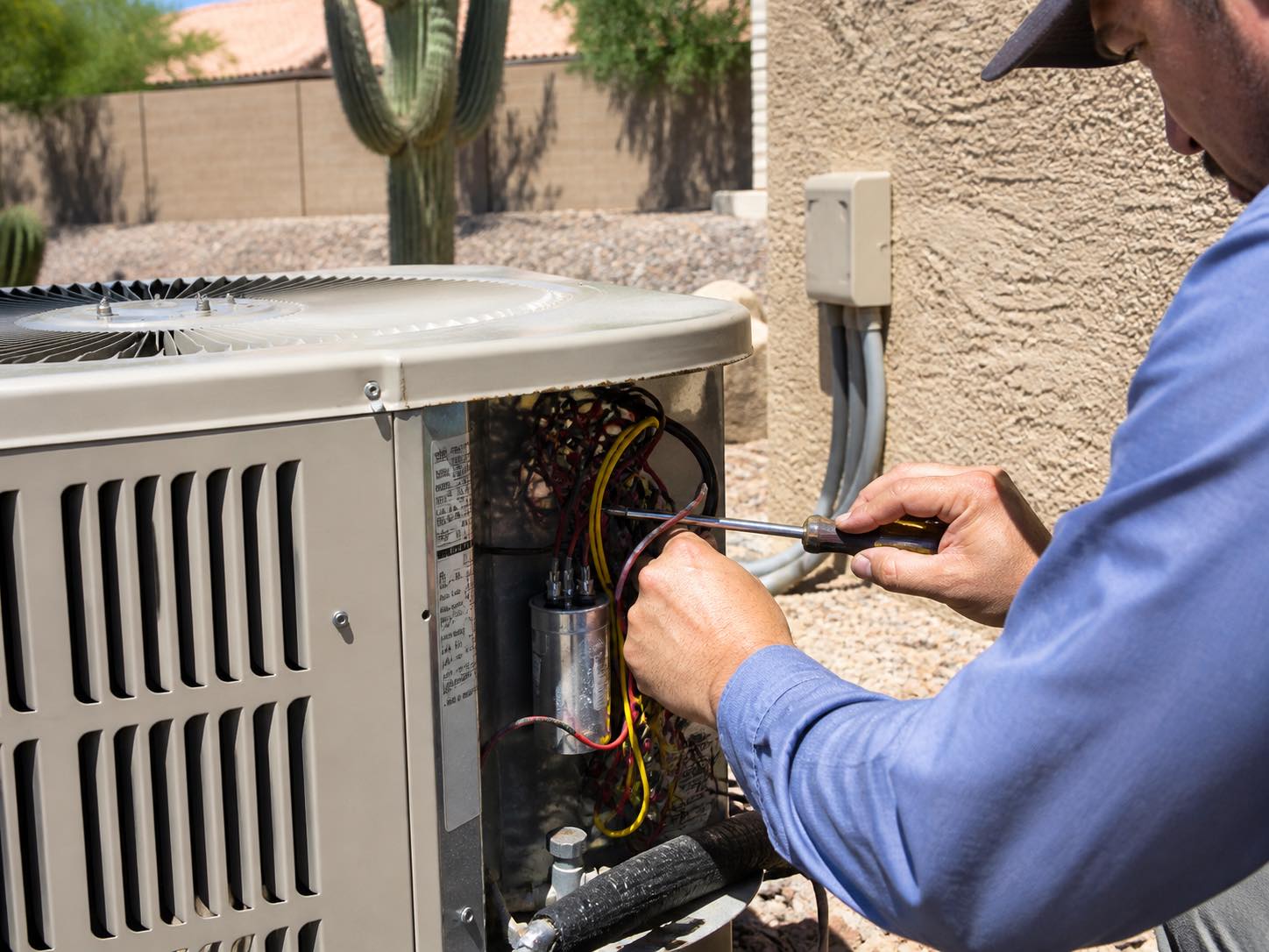A local HVAC pro working on a Phoenix homeowner's AC condenser